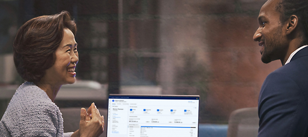 Two professionals engaging in a discussion with a laptop displaying data on the desk between them.