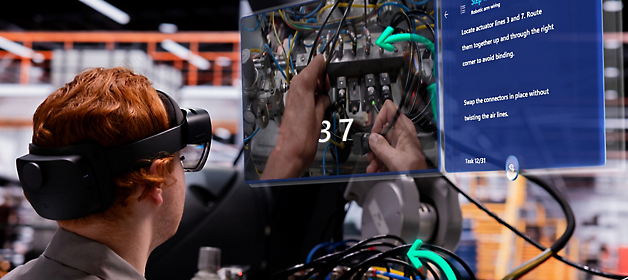 En tekniker, der bruger et virtual reality-headset, arbejder på et elektrisk panel, mens han refererer til en digital overlejringsvejledning.