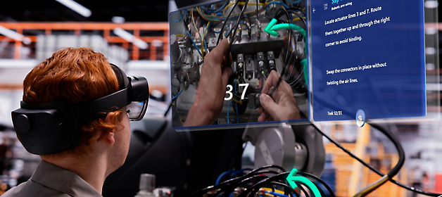 A technician wearing a virtual reality headset works on an electrical panel while referencing a digital overlay guide.