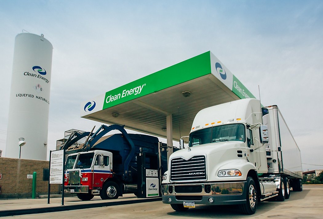 Lastbiler, der tanker på en ren energistation, der tilbyder flydende naturgas, under en klar himmel.