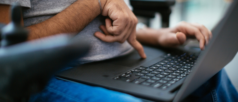 Close-up van de handen van een man die een laptop gebruikt, één hand op de trackpad en de andere maakt gebaren