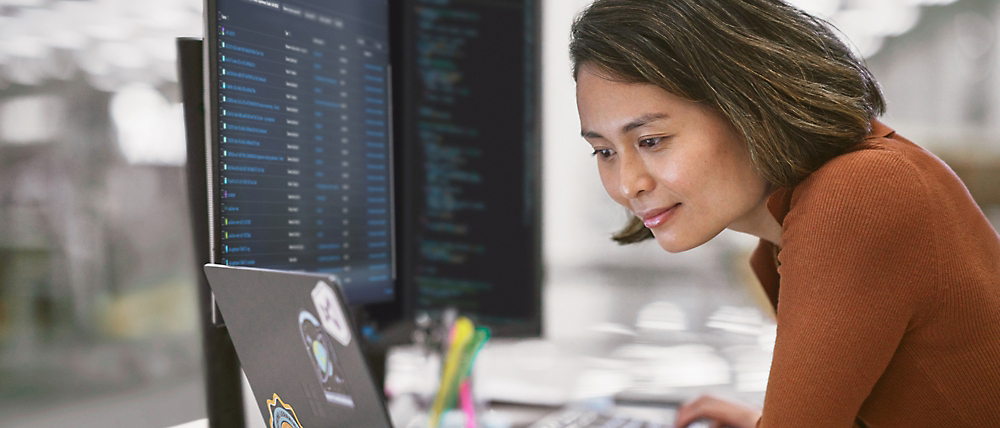 Una mujer se centra en programar en su equipo en una oficina moderna.