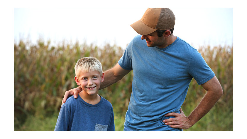 A farmer and his son in a corn field