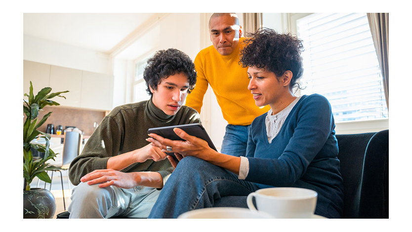 Three people in a home setting looking at a tablet