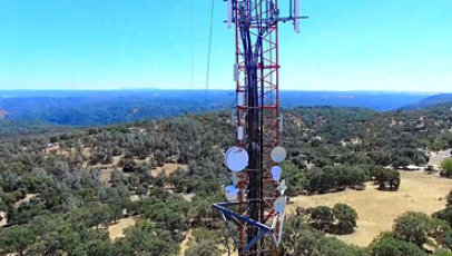 Tower in a rural area of California, rolling hills of evergreen trees extend far into the horizon.