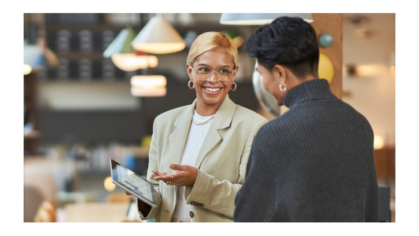 A businesswoman presents data to a client on her tablet.