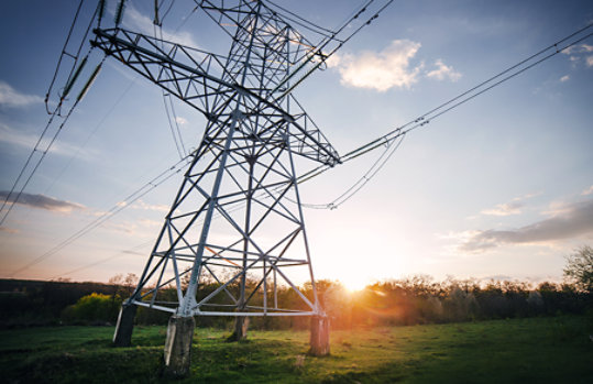 View of powerlines set against the sky and the setting sun.