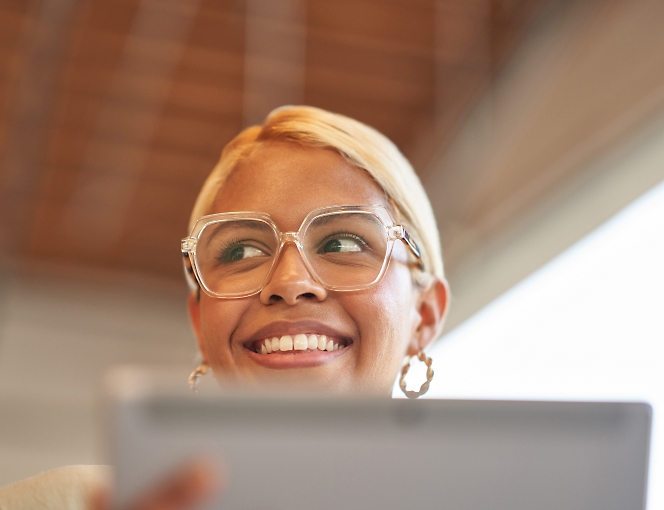 A woman wearing glasses is looking up at a tablet computer.