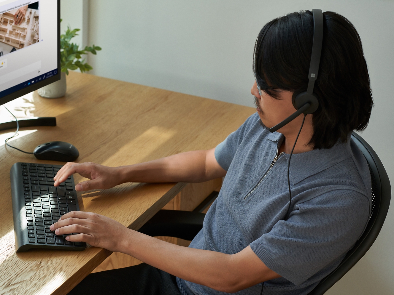 En mand bruger et headset, mens han arbejder på en computer.