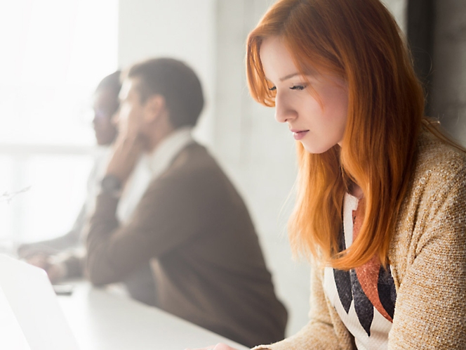 Une femme est assise à un bureau et travaille sur un ordinateur portable.