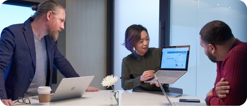 A group of people sitting around a table looking at a laptop.