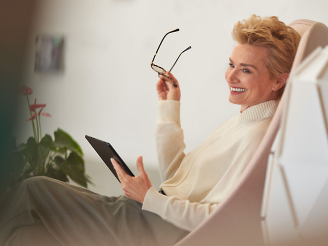 A person holding glasses and a tablet