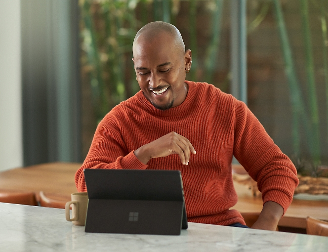 אדם היושב ליד שולחן עם מחשב נישא מסוג Surface Laptop של Microsoft.