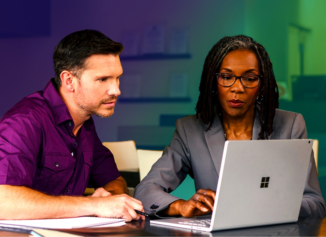 A man and woman are looking at a laptop.