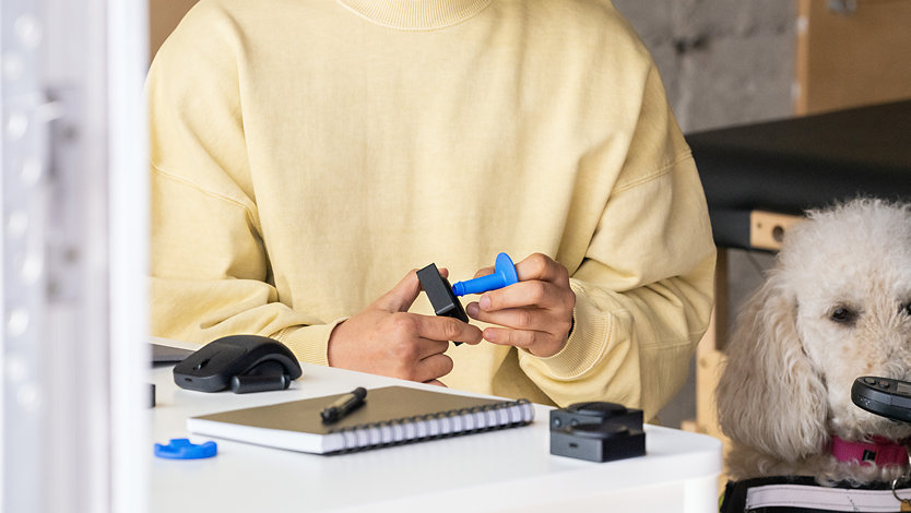 A person attaches a 3D printed button topper to a Microsoft Adaptive Button.