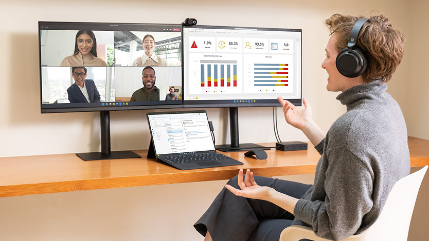 A person uses Surface Pro 9 for Business for a call while multitasking on two external monitors.