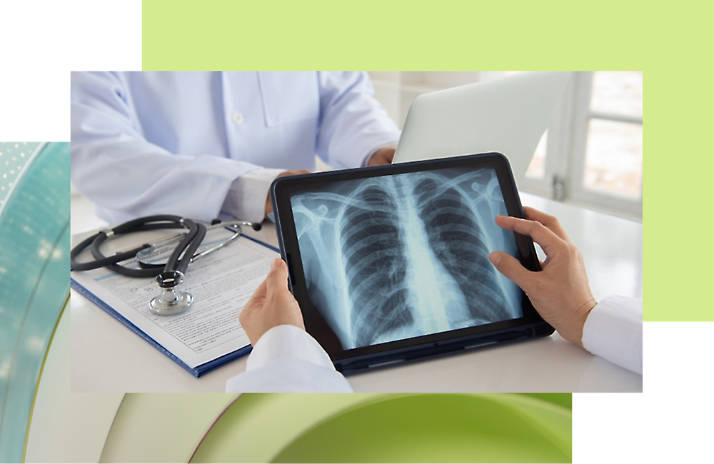 A doctor is looking at a tablet displaying an X-ray image while the another person sitting in opposite and working on his laptop.