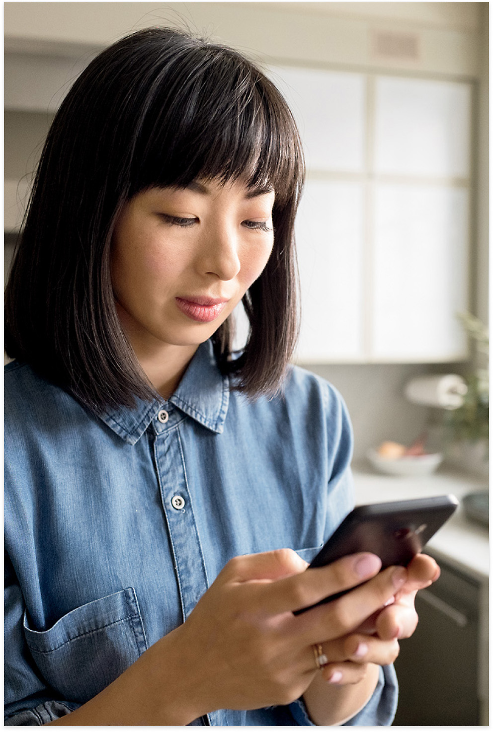 A woman wearing blue colored top checking her phone using both hands