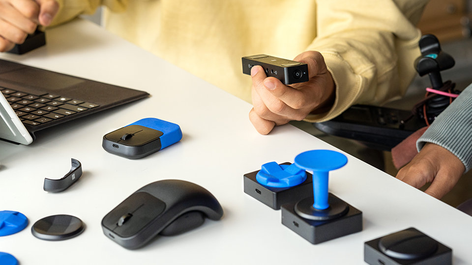 A person who uses a wheelchair sets up Microsoft Adaptive Hub and Buttons with 3D printed attachments. 