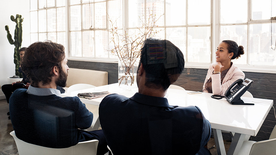 People attend a meeting in an office, suggesting the necessity of business-grade security for Surface devices. 