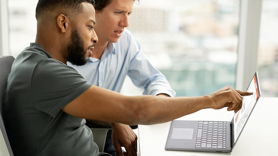 Surface Laptop 5 yrityksille: kaksi työtoveria tarkastelevat työtään turvallisesti.
