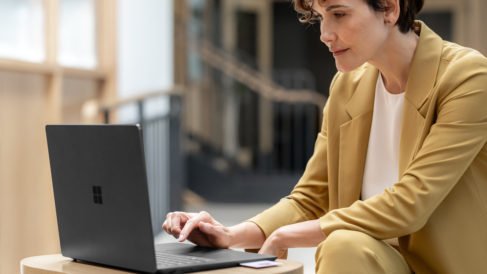Una persona usa Surface Laptop 6 para empresas, un PC con núcleo protegido, en un espacio público, sugiriendo la seguridad elevada del dispositivo.