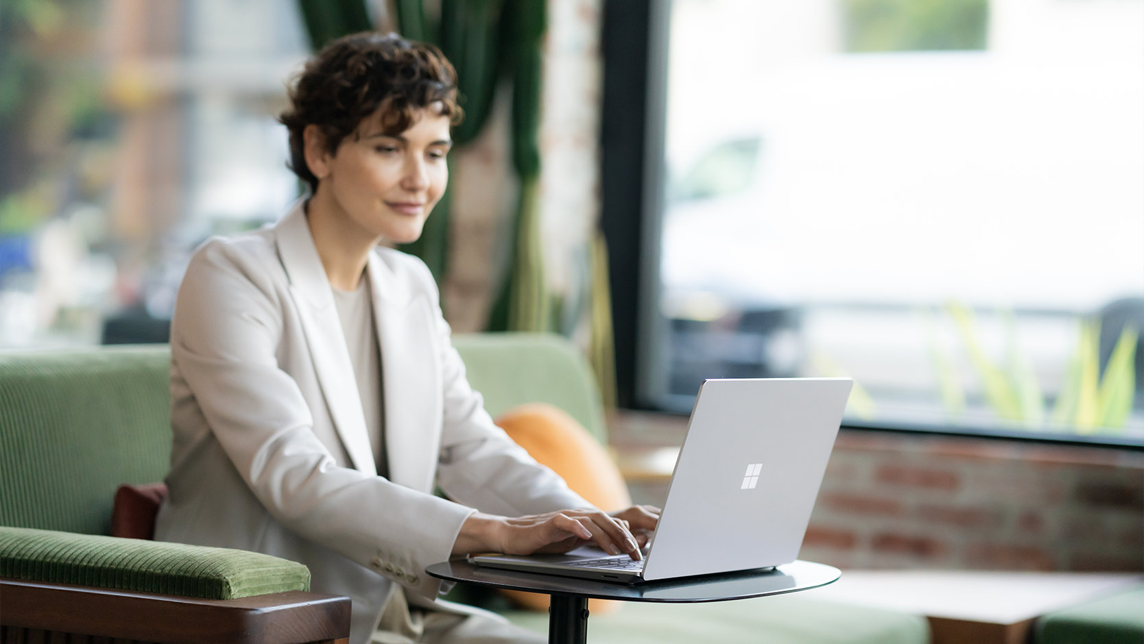 Una persona vestida de traje usa Surface Laptop 6 para empresas en un espacio público, indicando la seguridad del dispositivo.