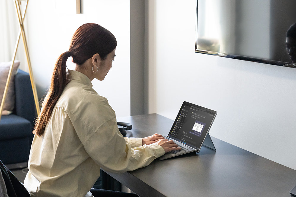 A person uses a Surface Pro Signature Keyboard while seated at a desk.