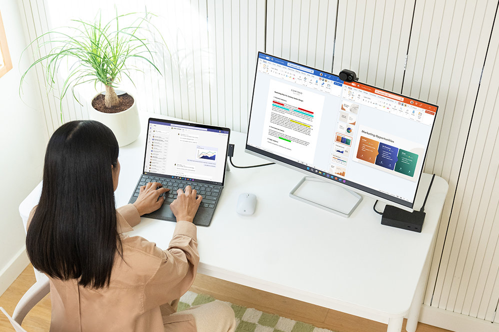En person sitter ved et skrivebord og bruker et Surface Pro Signature Keyboard.