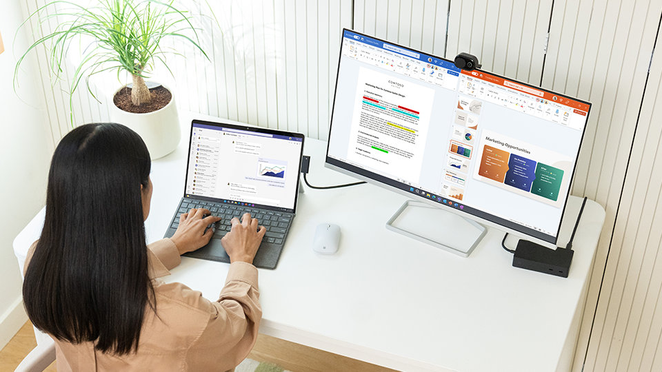 A person uses a Surface Pro Signature Keyboard for Business while seated at a desk.