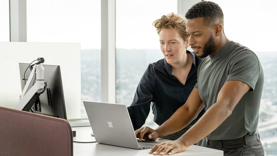 Zwei Personen verwenden ein Surface-Gerät und einen Monitor zugleich. Damit soll die Fähigkeit zum Anschluss von zwei Monitoren am Surface Thunderbolt™ 4-Dock for Business illustriert werden. 