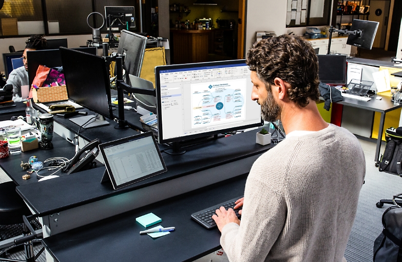 A person using a tablet device and one large desktop monitor to create floorplans.