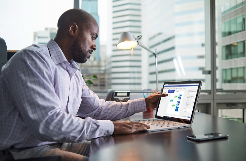 A person at their desk creating an org chart using a touchscreen laptop.