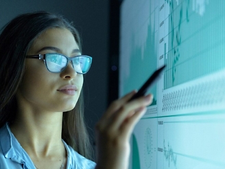 A person wearing glasses and holding a pen