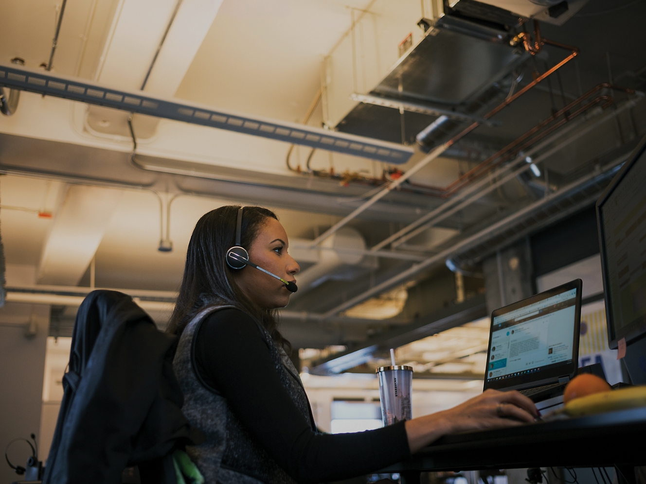 Eine Frau, die ein Headset trägt und an einem Schreibtisch arbeitet