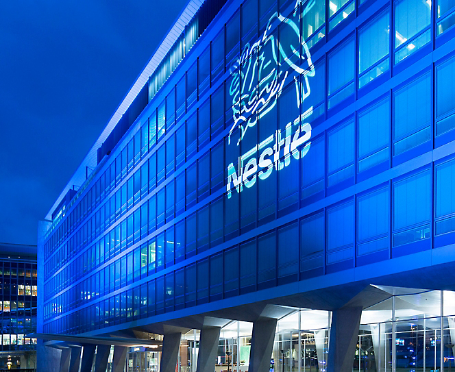 อาคารที่สว่างไสวในยามค่ำคืนโดยมีโลโก้ Nestle อยู่บนนั้น