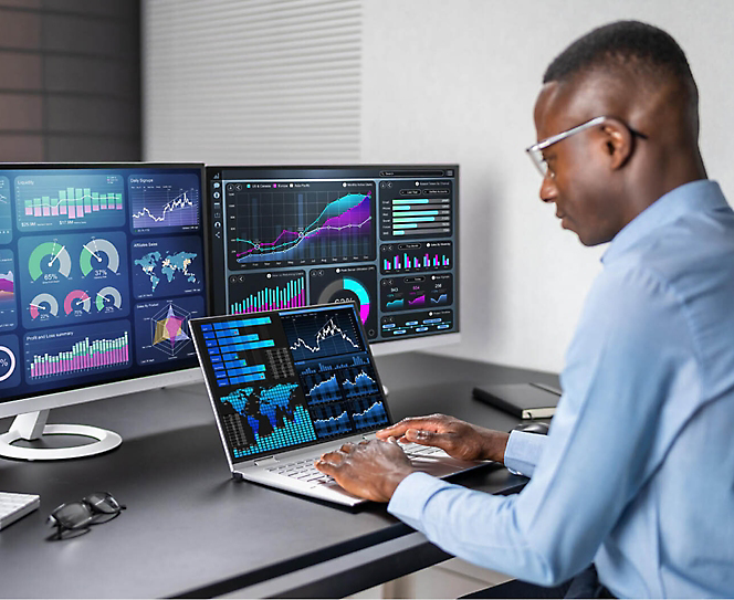 A person working on laptop with multiple monitors