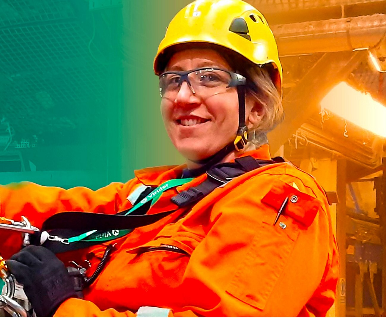 A woman wearing a helmet and safety glasses in front of a machine.