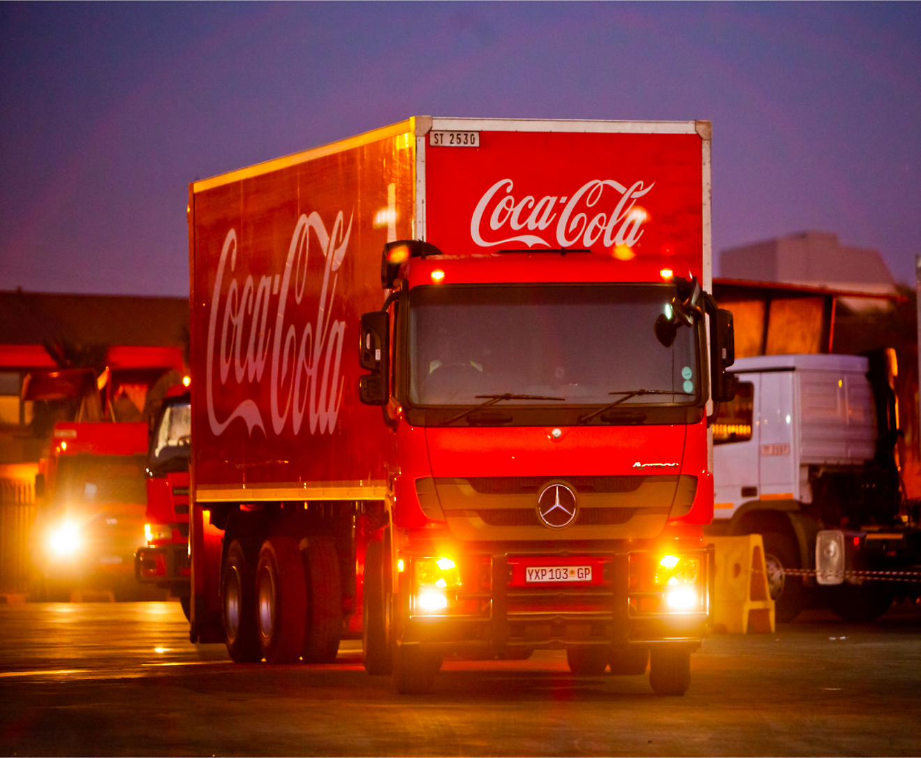 A red coca cola truck is parked in a parking lot.