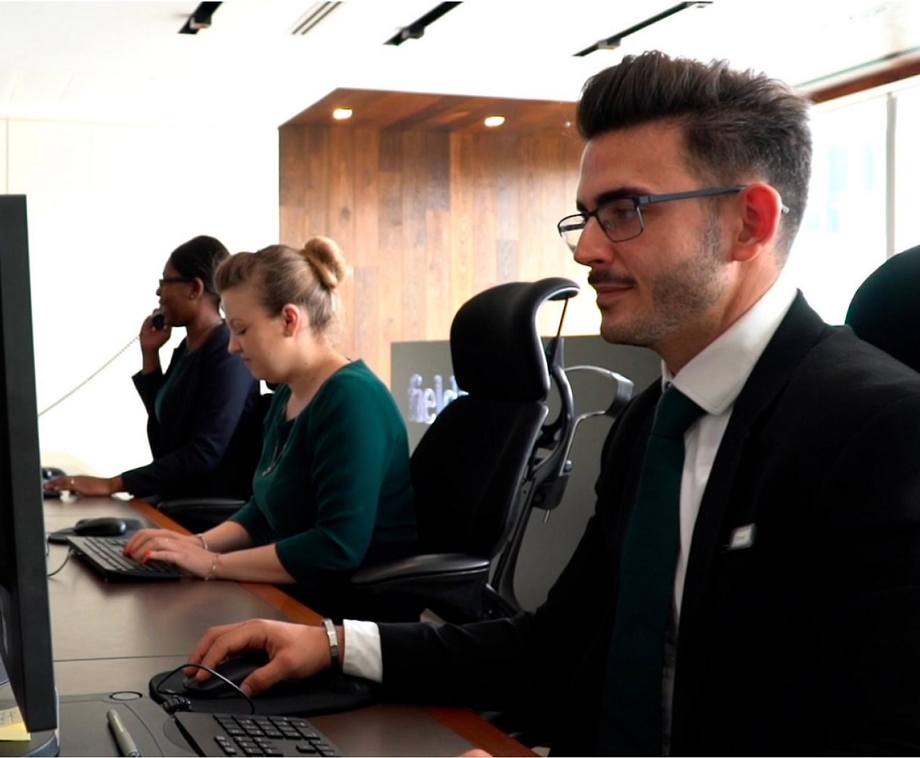 Számítógépen dolgozó emberek egy csoportja egy irodában.