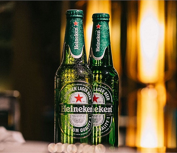 Two bottles of heineken sitting on a table.