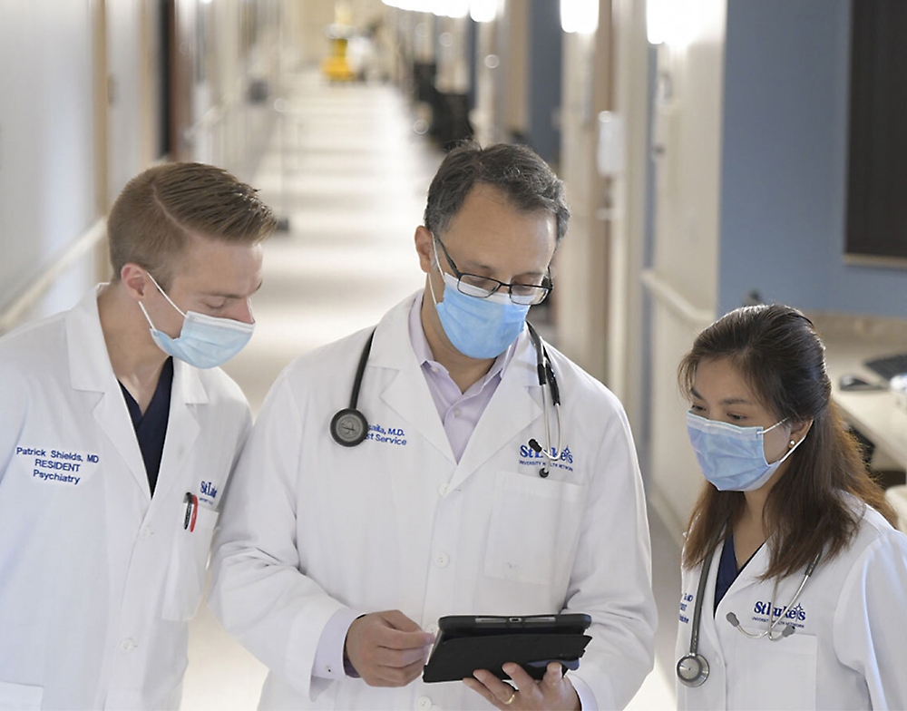 A group of doctors, wearing face masks, watching a phone