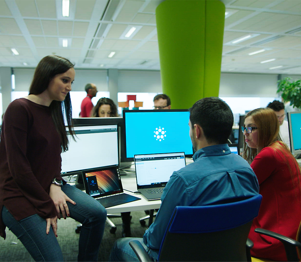 A group of people sitting around a table with computers