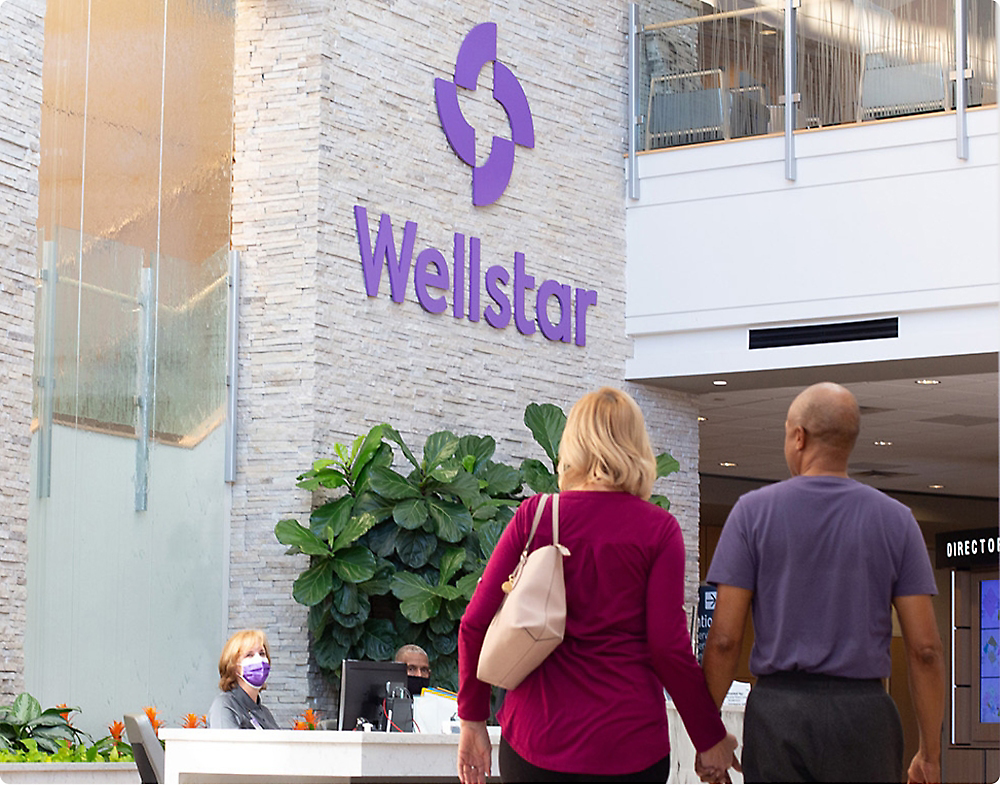 Two people walking in front of the reception at Wellstar