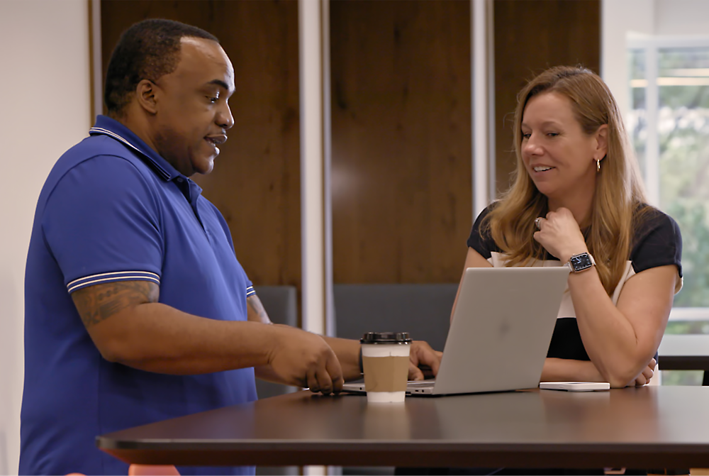 Two people sitting and looking at the laptop.