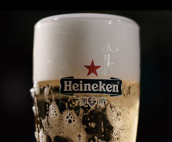 A close-up of a Heineken beer glass filled with foamy, chilled beer.