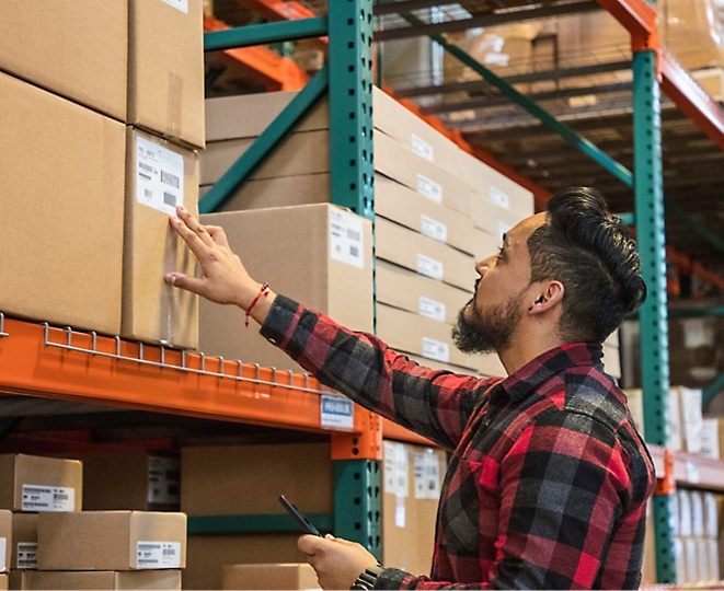 A man looking at boxes in a warehouse.