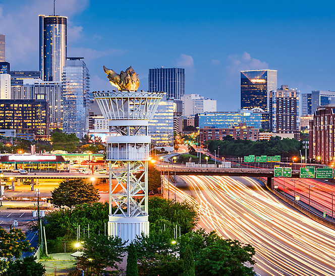 Atlanta skyline at dusk with the olympic torch tower and busy highway traffic.