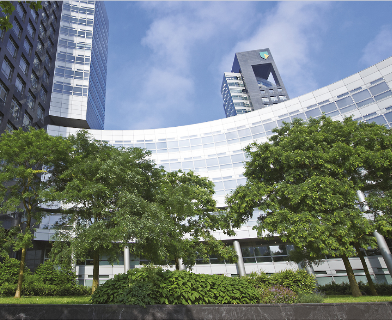 An office building with garden in front with green trees