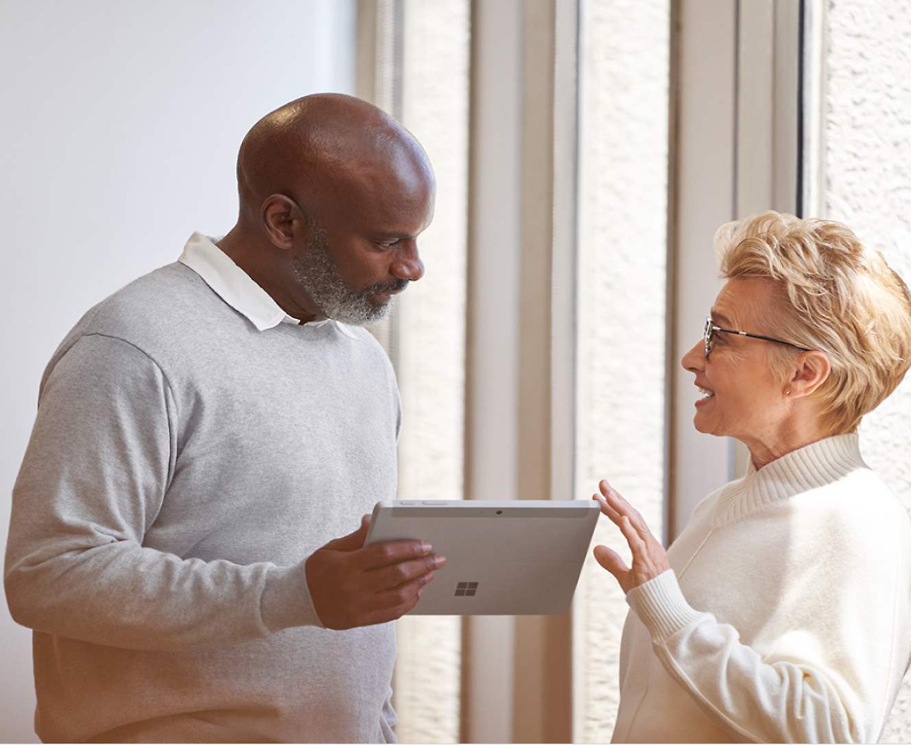 Een man die een surface pro vasthoudt die met een vrouw praat